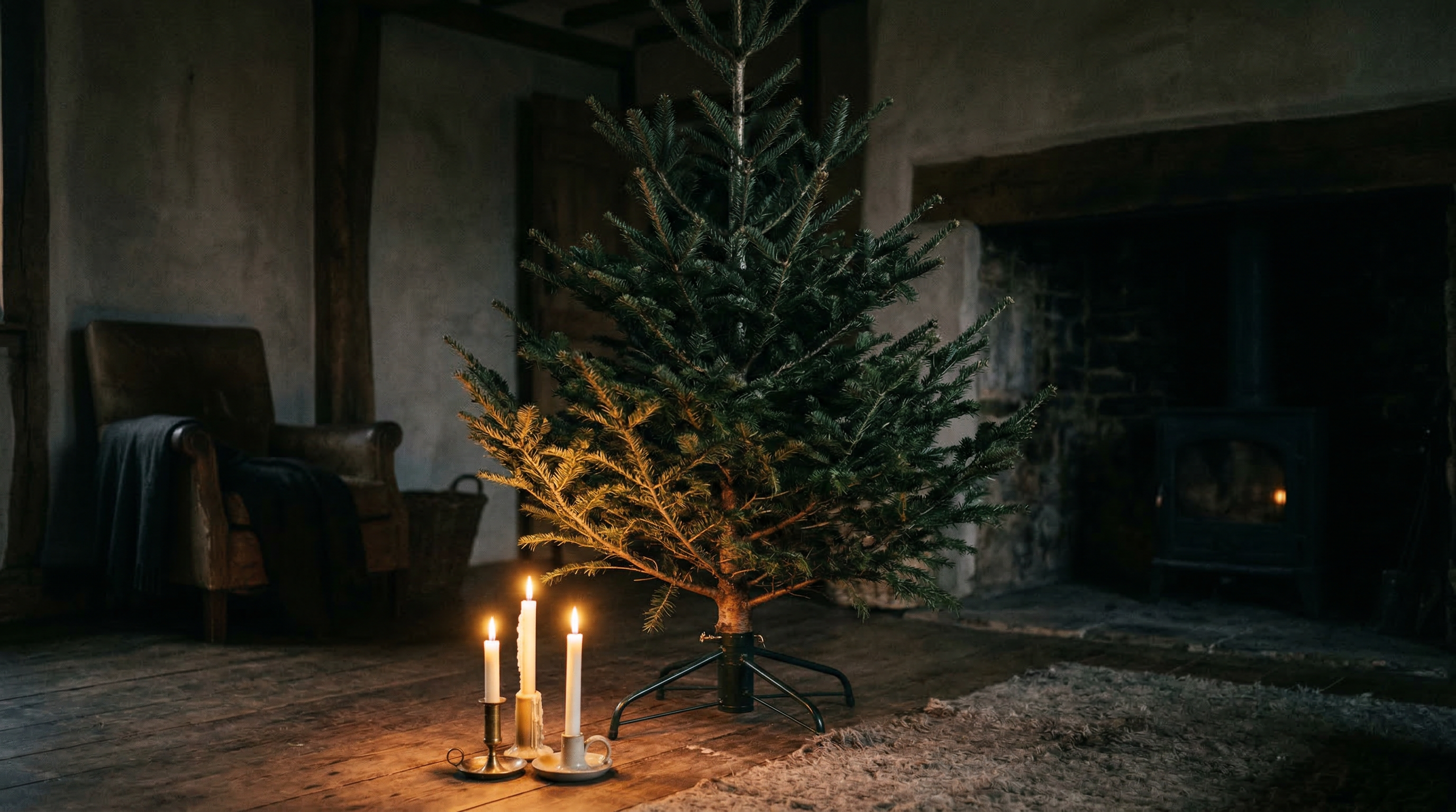 A bare Christmas tree in a candlelit room